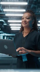 Poster - Vertical Screen. Portrait of Black Female IT Specialist Using Laptop, Standing in Data Center. System Administrator Works on Web Services. Cloud Computing, Server Analytics, Cyber Security