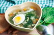 Green borsch with sorrel, parsley, egg and grens in the bowl form of heart with spoon on wooden background