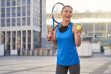 Excited Attractive Middle Aged Sportswoman Holding Tennis Racket And A Ball Ready For Playing Tennis In The City