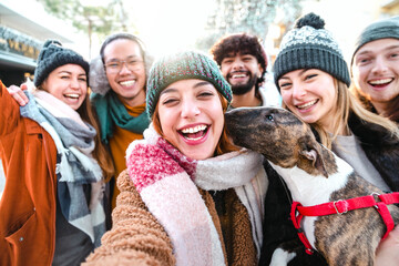 Wall Mural - Happy millenial friends taking selfie portrait outside - Group of young people having fun walking on city street enjoying winter sunny day - Happy lifestyle concept - Backlight and bright filter