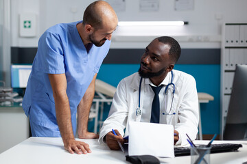 Wall Mural - African american therapist doctor explaining sickness expertise checking medicine prescription discussing healthcare treatment. Medical team working in hospital office monitoring disease symptoms