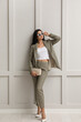 © New Africa - Full length portrait of beautiful woman in formal suit near light grey wall. Business attire