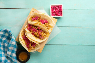 Wall Mural - Pork meat tacos called cochinita pibil on a turquoise background. Mexican food