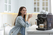 © New Africa - Young woman enjoying fresh aromatic coffee near modern machine in kitchen