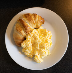 Poster - Top view of scrambled eggs and a croissant on a white plate on the table