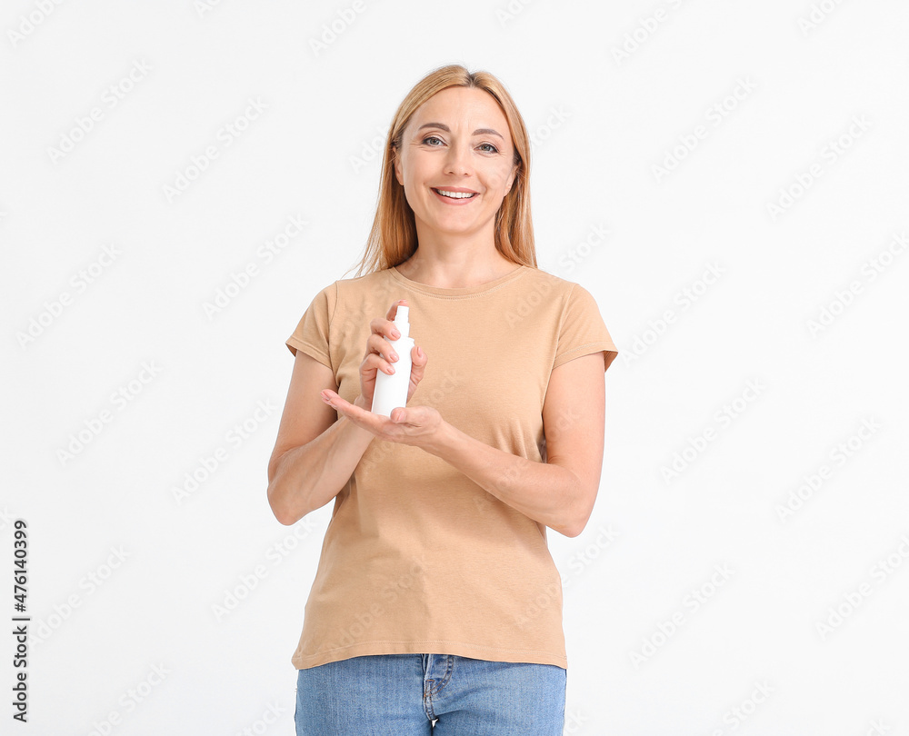 Mature woman with mosquito repellent on light background