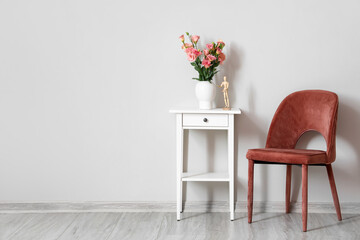 Wall Mural - Modern chair and table with vase, roses and mannequin near light wall