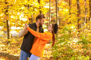 Young fashionable couple dancing in beautiful autumn park