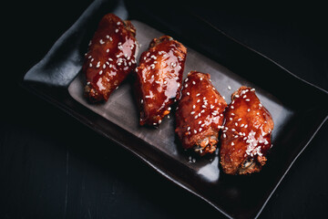 Wall Mural - Fried chicken wings with spicy and sweet Korean sauce topped with white sesame seeds