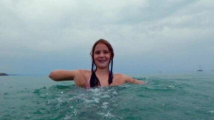 water surface pov of smiling redhead child girl has fun splashing sea water on camera. slow motion