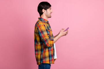 Sticker - Photo of attractive cute guy dressed checkered clothes smiling typing modern device looking empty space isolated pink color background