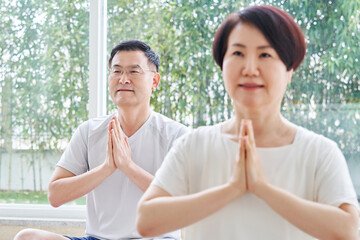 Middle-aged couple exercising in yoga poses at home