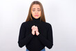 Sad Young caucasian girl wearing black turtleneck over white background feeling upset while spending time at home alone staring at camera with unhappy or regretful look.