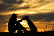 © Diana Badmaeva - Silhouette of a man and a Malinois dog on a sunset background