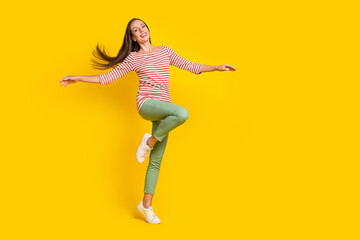 Poster - Photo of funny adorable young woman wear striped shirt smiling having fun arms sides empty space isolated yellow color background