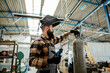 © Dusan Petkovic - A worker with a protective mask on his head unscrews the valve on the gas bottle and prepares for welding. A worker welding in the workshop