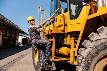 Wall Mural - A senior heavy industry worker is climbing the bulldozer and getting ready to drive it. A driver climbing the bulldozer.