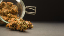 Dry Cannabis Buds Flower Outside A Jar Glass On The Table With A Black Background