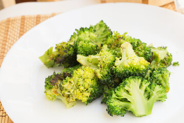 fried inflorescences of broccoli with provencal herbs on white plate