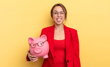 Businesswoman With Cheerful And Rebellious Attitude, Joking And Sticking Tongue Out. Piggy Bank Concept