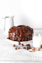 Canvas Print - Vertical shot of a delicious chocolate cake surrounded by hazelnuts and chocolate bars