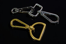 Set Of Metal Carabiner On A Black Background Top View. Accessories For Bags. A Small Carabiner That Is Used To Craft Accessories. Bag Accessories. Metallic Products For The Clothing Industry.