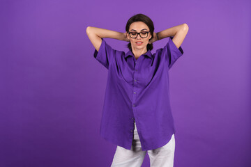 Wall Mural - Young woman in a shirt with short sleeves on a purple background, with makeup, lipstick on her lips and stylish glasses posing on the background