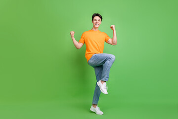 Poster - Full size photo of cheerful happy young man winner rise fists good mood isolated on green color background