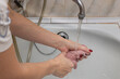 female hands rinse a rag under running tap water