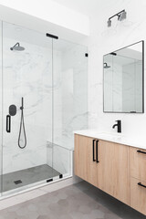 Wall Mural - A beautiful luxury, modern bathroom with a light wood cabinet, walk-in shower with marble tiled walls, and black faucets and hardware.