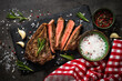 Beef steak on black background with spices. Grilled beef steak striploin medium rare on slate serving board. Top view
