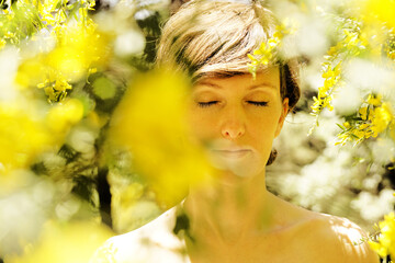 Sticker - Scenic shot of a Caucasian topless short-haired woman surrounded by yellow shrub flowers