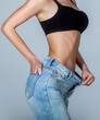 © Yevhen - Weight loss concept. Thin woman in big pants, weight loss concepts. Slim girl wearing oversized pants. Woman shows weight loss. Dieting. Woman showing slim body after sport trainings, healthy eating