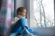 © Jacek - Sad face of a child, 7 years old boy, at home by the window.