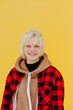 © bodnarphoto - Positive teen girl with blond hair isolated on yellow wall background, looking at camera and smiling. Vertical.