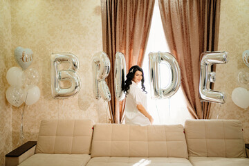 Wall Mural - bride in white coat in a room of her house by sofa with balloons.