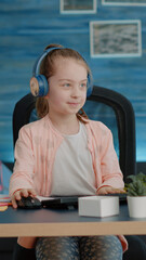 Wall Mural - Little child waving at video call camera while wearing headphones for online class lesson with teacher. Young girl talking on video conference on computer for remote education courses