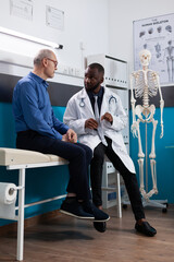 Wall Mural - Retired old man discussing sickness symptoms to specialist therapist during medical appointment in hospital office. Physician doctor explaining disease diagnosis working at healthcare treatment