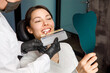 © Aleksandr Rybalko - Smiling young woman. Cosmetological teeth whitening in a dental clinic. selection of the tone of the implant tooth