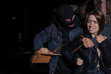 Woman Fighting With Thief While He Trying To Steal Her Bag Outdoors At Night. Self Defense Concept