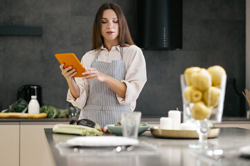 Wall Mural - Young housewife looking for new cooking ideas on internet