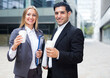 © JackF - Businessman and his woman colleague in suit are standing with folder and coffee near the office.