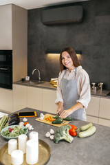 Wall Mural - Long-haired young housewife cooking in the kitchen