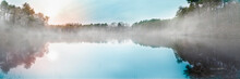 Peaceful Foggy Pond At Dawn On Cape Cod. The Glowing Sun And Pine Tree Forest Reflected On The Lake.