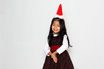 Little brunette Latina girl in red party dress and Christmas hat excited and happy for the arrival of December and celebrate Christmas and New Years
