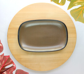 Wall Mural - dish is placed on a round wooden table with monstera palm leaves for decoration