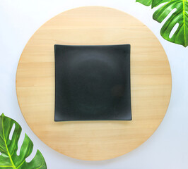 Wall Mural - dish is placed on a round wooden table with monstera palm leaves for decoration