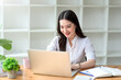 © amnaj - Portrait of smiling beautiful Asian businesswoman enjoy the idea sitting with laptop computer at office.