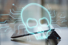 Close Up Of Tablet With Abstract Glowing Digital Skull On Blurry Background. Hacker, Technology And Virus Concept. Double Exposure.