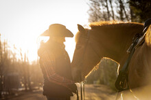 Cowgirl With Horse At Sunset
